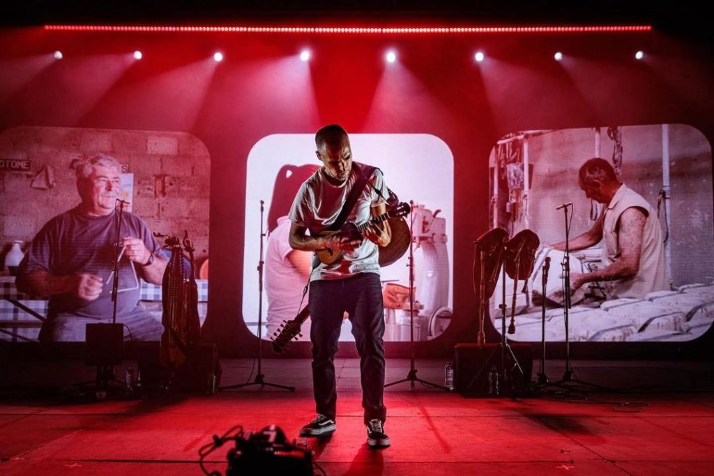 Musician playing a stringed instrument on a red-lit stage